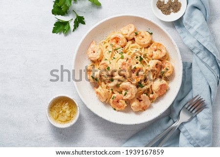 Pasta spaghetti with grilled shrimps bechamel sauce. Spaghetti with seafood rich cream. Cooking mediterranean food with savory prawns, copy space top view, blue table, italian cuisine
