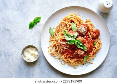 Pasta spaghetti with meat ball in tomato sauce on a plate over light grey slate, stone or concrete background. Top view with copy space.