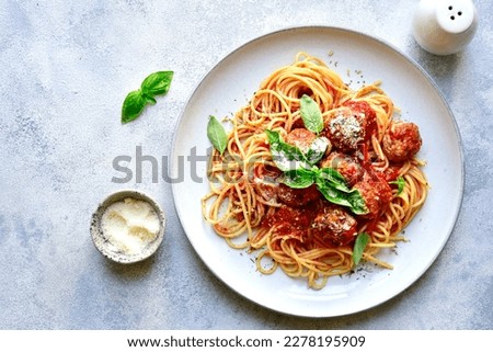 Pasta spaghetti with meat ball in tomato sauce on a plate over light grey slate, stone or concrete background. Top view with copy space.