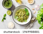 Pasta spaghetti with pesto sauce and fresh basil leaves in grey bowl. Light grey background.Top view.