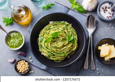 Pasta spaghetti with pesto sauce and fresh basil leaves in black bowl. Grey background. Top view. - Powered by Shutterstock