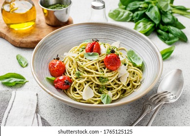 Pasta spaghetti with pesto sauce and fresh basil leaves in gray bowl. Light grey background - Powered by Shutterstock