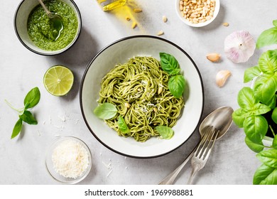 Pasta spaghetti with pesto sauce and fresh basil leaves in grey bowl. Light grey background.Top view.