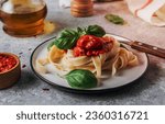 Pasta Tagliatelle Bolognese with meat tomato sauce and fresh basil leaves on white plate. Light gray table. Selective focus