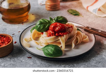Pasta Tagliatelle Bolognese with meat tomato sauce and fresh basil leaves on white plate. Light gray table. Selective focus - Shutterstock ID 2360316721