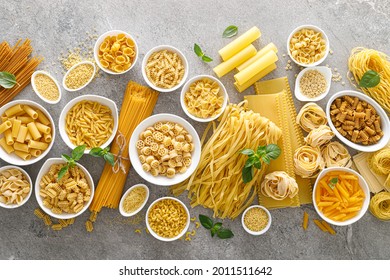Pasta. Various kinds of uncooked pasta and noodles over stone background, top view with copy space for text. Italian food culinary concept. Collection of different raw pasta on cooking table - Shutterstock ID 2011511642