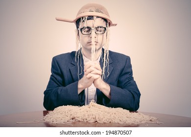 Pastafarian wearing a colander praying for pasta to the Flying Spaghetti Monster.