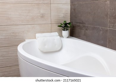 Pastel beige color bathroom with white bathtub and pillow and porcelain glazed stoneware tile marble walls  - Shutterstock ID 2117165021