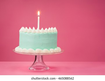 Pastel Blue Birthday Cake Over Pink Background With One Candle.