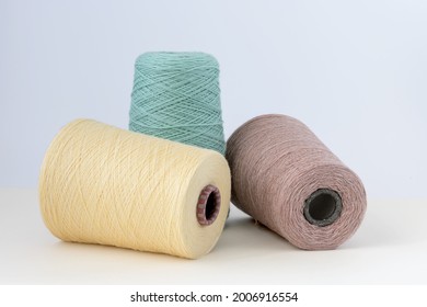 Pastel color bobbins of wool yarn for hand and machine knitting on a white background