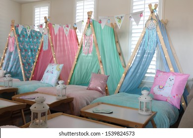 Pastel colored teepee's all set up for a girl's birthday party sleepover. 