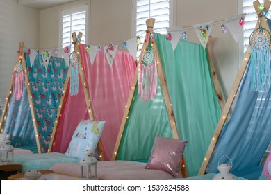 Pastel colored teepee's all set up for a girl's birthday party sleepover. 