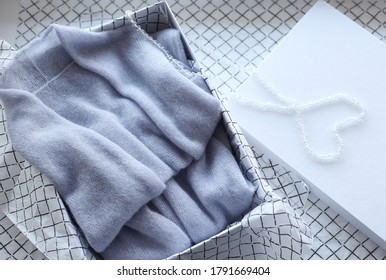 Pastel Colored Womens Clothing Folded In A Box On A White Background. Gift Organization Concept