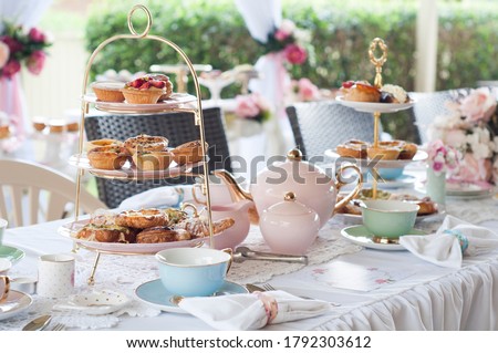 Pastel high tea set up featuring pastel pink, blue, yellow and green Royal Doulton tea set and an assortment of sweet and savoury pastries.