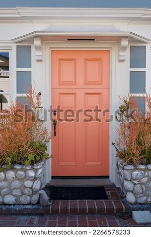 Pastel peach front door of a traditional 1930’s beach cottage