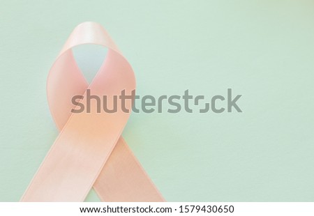 pastel pink color ribbon was done to symbol of anti breast cancer on pastel blue color background.