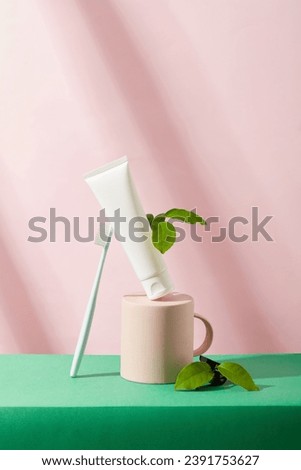 The pastel pink cup is turned upside down. Unbranded toothpaste tube and toothbrush. Mockup for a new product launch advertisement with ingredients from green tea and bamboo charcoal.