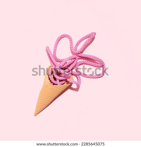 Pastel pink fabric cord in an ice cream cone, creative summer holiday concept, melting fruit flavor cream idea, stylish nautical cord. 