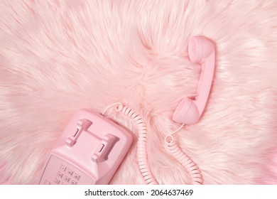 Pastel pink retro telephone handset and pastel pink faux fur background. Vintage aesthetic 80s or 90s fashion background. Romantic communication idea. Romantic valentines day idea.