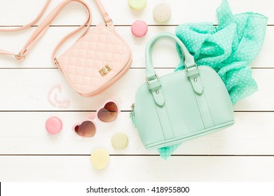 Pastel theme mood board with fashion accessories (bags, sunglasses, scarf) for girls. White rustic wooden background. Flat lay composition (from above, top view).