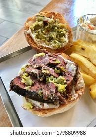 Pastrami Burger With Mustard And Pickles Served With Potatoes.