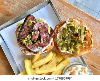 Pastrami Burger With Mustard And Pickles Served With Potatoes.