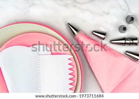 Pastry bag cream pink injector for cake dessert decoration, supplies kit icing piping, stainless steel nozzle tips. DIY tools on white marble background. Cooking bakery concept with copy space