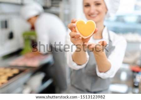 Pastry chef baking heart shaped cookies giving a thumbs-up