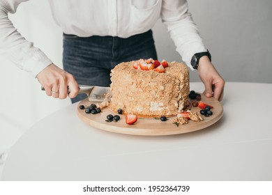 The pastry chef is cutting the cake. A delicious honey cake is cut with a knife. Close-up of honey cake