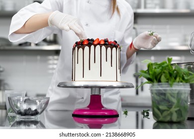 Pastry chef decorates the cake with chocolate levels of berries and mint.