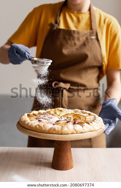 Pastry\
chef dusting icing sugar on apple pie, rotating cake stand,\
decorating turntable, powdered sugar,\
confectioner