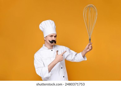 Pastry chef with fake mustache pointing at big whisk on orange background - Powered by Shutterstock