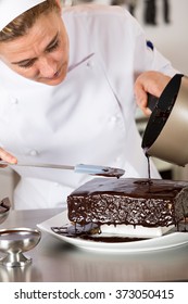 Pastry Chef In The Kitchen Decorating A Cake Of Chocolate