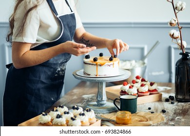 Pastry chef in the kitchen decorating a cake of chocolate,fruit,candies,Confectioner is decorating chocolate cake,cooking class, culinary, bakery, food and people concept
