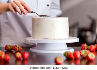 Pastry Chef, Makes A Wedding Cake With His Own Hands And Decorates Him With Berries And Flowers. Background Image. Copy Space. Selective Focus.