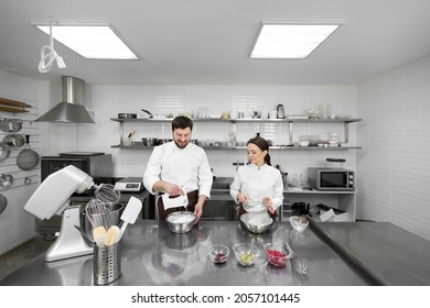 Un chef pastelero, un hombre y una mujer en una cocina profesional preparan una tarta de esponja, mezclan los ingredientes y sientan la harina.