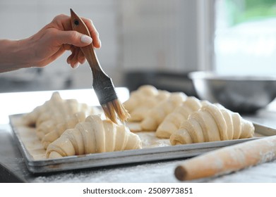 Pastry chef smearing egg yolk on raw bun with silicone brush closeup. - Powered by Shutterstock