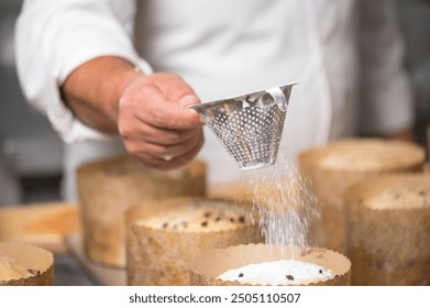 Pastry chef Topping Traditional Italian panettones with powdered sugar. - Powered by Shutterstock