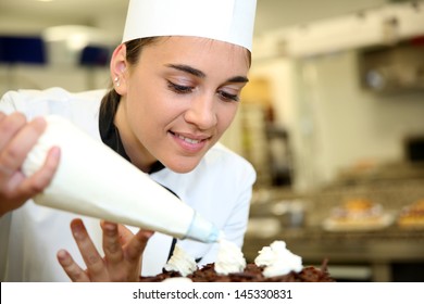 Pastry Cook Putting Whipped Cream On Cake