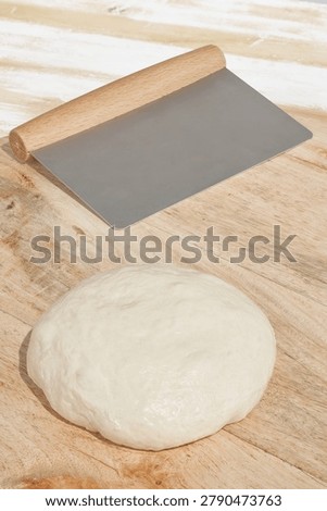Pastry scraper arranged within a baking preparation scene involving dough handling, bread making and pastry production. Essential bakery utensil used for shaping, portioning and working with dough during artisan recipes and oven baking. Flour, ingredients and practical tools accompany activities connected to breadmaking, confectionery and homemade baked goods. Warm textures, wooden surfaces and simple materials define environments associated with bakeries, pastry workshops and domestic kitchens. Functional equipment, traditional techniques and everyday ingredients reflect longstanding baking practices and the preparation of breads, pastries and baked products.