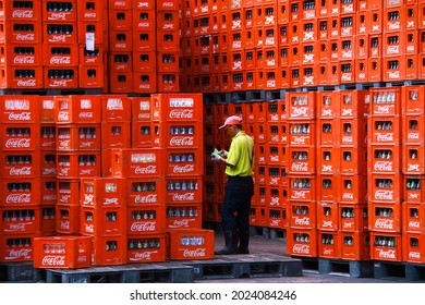 PASURUAN, INDONESIA – JANUARY 10, 2013 : A workerS control a stack of crates of empty Coca-Cola bottles. 
