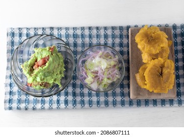 Patacones, Salsa And Guacamole On A White Restaurant Table. Overhead Point Of View.