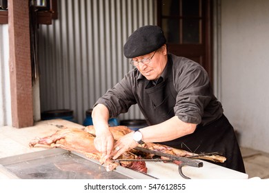 PATAGONIA, CHILE - NOV 6, 2014:  Unidentified Chilean Man Prepares A Traditional National Food Of Chile Asado. Chilean People Are Of Mixed Spanish And Indigenous Descent