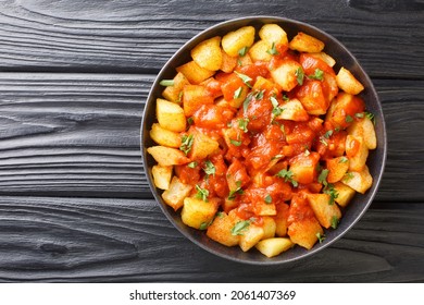 La receta de Patatas Bravas fritó patatas con salsa de bravas cerca del plato en la mesa. Vista horizontal superior desde arriba