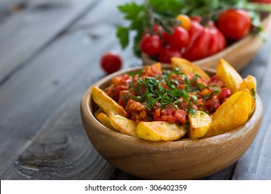 Patatas Bravas, traditional Spanish tapas, baked potatoes with spicy tomato sauce in wooden bowl on wooden table. selective focus - Shutterstock ID 306402359
