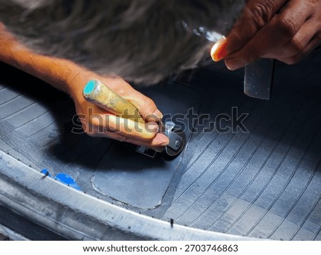 A patch is being made to a nail hole in a truck tire.