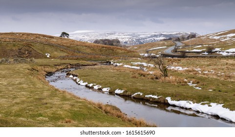 Patches of winter snow lie on pasture beside Widdale Beck river in Widdale valley near Hawes in England's Yorkshire Dales.
