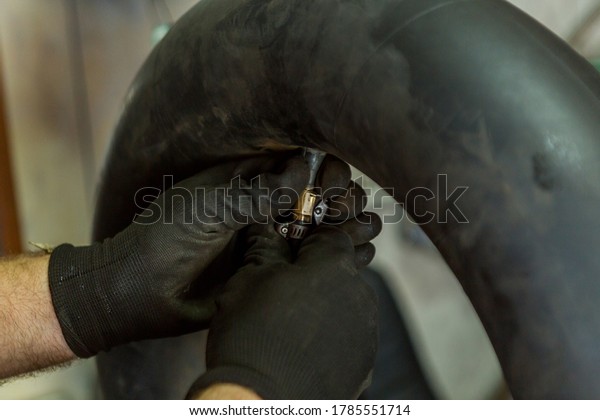 Patching inner tube for tractor ,car repair\
shop.Inflating inner tube.Hand on the\
valve.