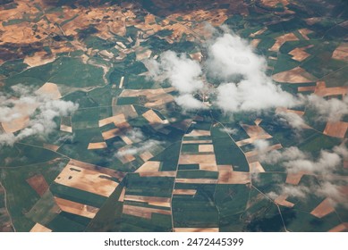 Patchwork landscape with white clouds covering a little village. Aerial view from fertile land Spain. Satellite or aircraft view. Raining over my head concept. High quality photo