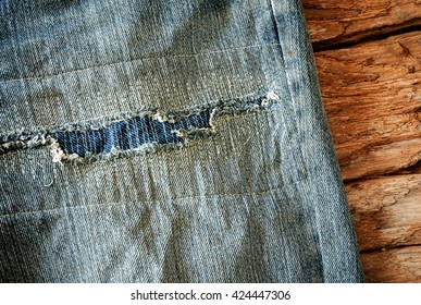 Patchwork on worn out blue jeans of young geologist tough field work.